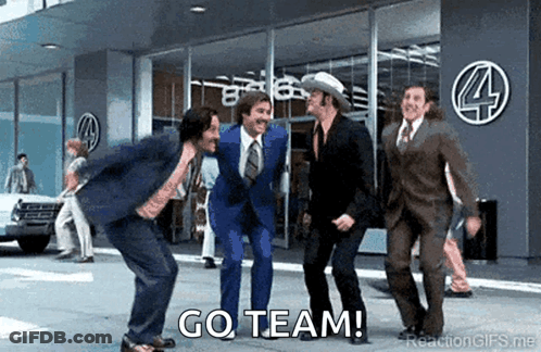 A Group Of Men In Suits And Ties Are Dancing In Front Of A Building With The Words Go Team Written On The Bottom . GIF