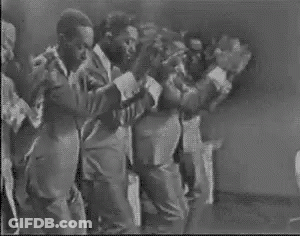 A Group Of Men In Suits And Ties Are Dancing On A Stage . GIF