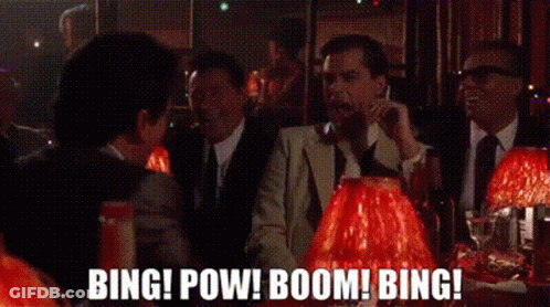 A Group Of Men In Suits And Ties Are Sitting At A Table In A Bar Talking On Their Cell Phones . GIF