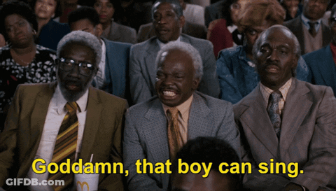 A Group Of Men In Suits And Ties Are Sitting In A Crowd And One Of Them Is Saying Goddamn That Boy Can Sing GIF