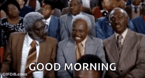 A Group Of Men In Suits And Ties Are Sitting In A Room With The Words `` Good Morning '' Written On The Screen . GIF