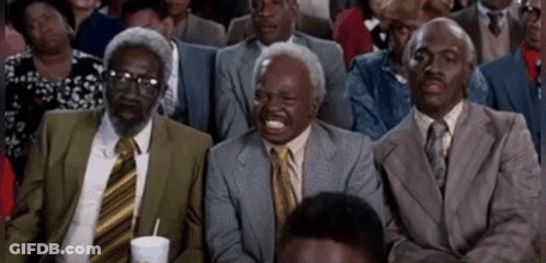A Group Of Men In Suits And Ties Are Sitting In A Row Laughing . GIF