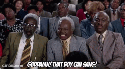 A Group Of Men In Suits And Ties Are Sitting In A Theatre Laughing . GIF