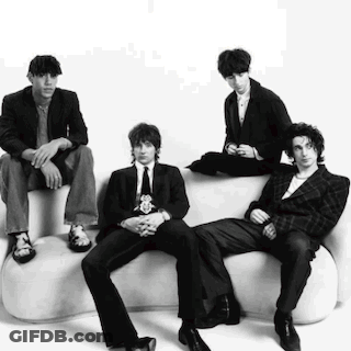 A Group Of Men In Suits And Ties Are Sitting On A White Couch . GIF