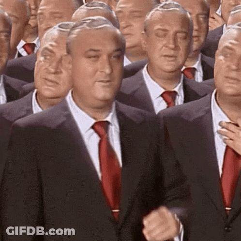 A Group Of Men In Suits And Ties Are Standing In A Row . GIF