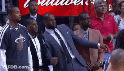 A Group Of Men In Suits And Ties Are Standing In Front Of A Budweiser Sign . GIF