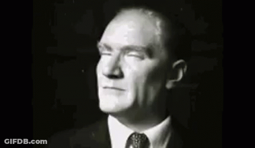 A Group Of Men In Suits And Ties Are Standing Next To Each Other In A Room . GIF