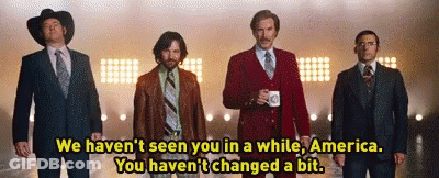 A Group Of Men In Suits And Ties Are Standing Next To Each Other In Front Of A Stage . GIF