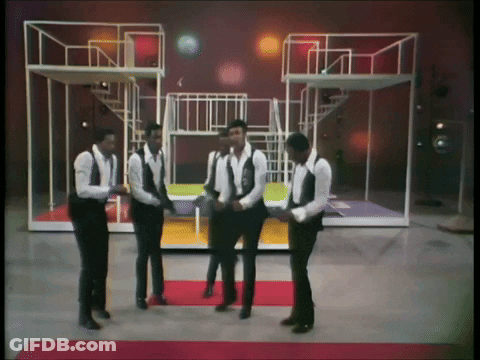 A Group Of Men In Suits And Vests Are Dancing On A Stage GIF