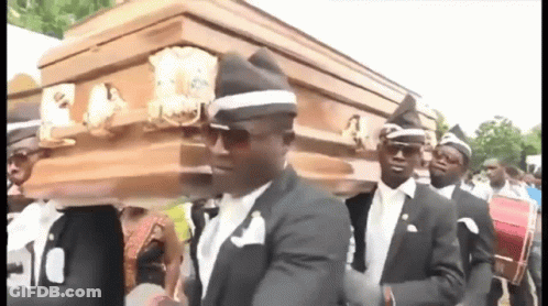 A Group Of Men In Suits Are Carrying A Coffin . GIF