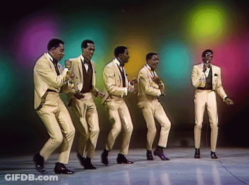 A Group Of Men In Suits Are Dancing And Singing Into Microphones GIF