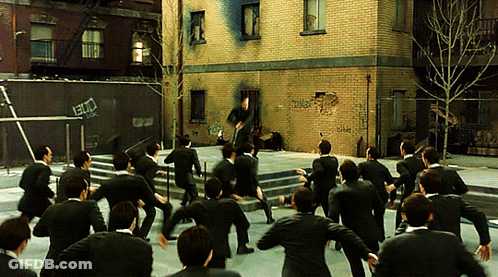 A Group Of Men In Suits Are Dancing In Front Of A Brick Building That Has Graffiti On It That Says ' Ec ' GIF