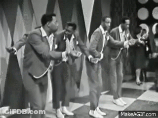 A Group Of Men In Suits Are Dancing On A Stage . GIF