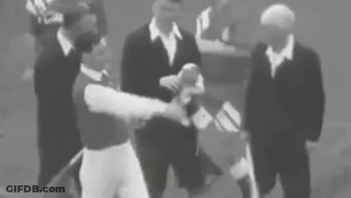 A Group Of Men In Suits Are Standing Around A Baseball Player . GIF