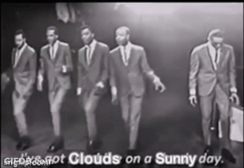 A Group Of Men In Suits Are Walking In A Row . GIF