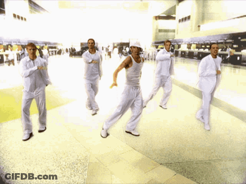 A Group Of Men In White Are Dancing In A Hallway GIF