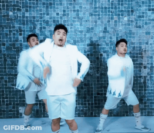 A Group Of Men In White Clothes Are Dancing In Front Of A Blue Tiled Wall GIF