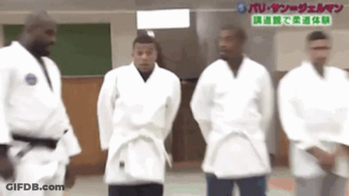 A Group Of Men In White Karate Uniforms Are Standing Next To Each Other . GIF