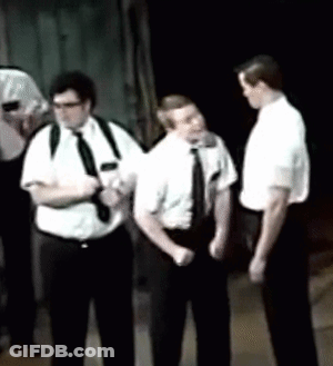A Group Of Men In White Shirts And Black Ties Are Standing In A Dark Room GIF