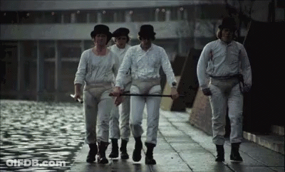 A Group Of Men In White Shirts And Hats Are Walking Down A Street . GIF