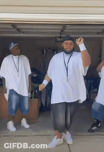 A Group Of Men In White Shirts Are Dancing In A Garage Doorway . GIF