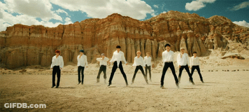 A Group Of Men In White Shirts Are Standing In A Desert GIF