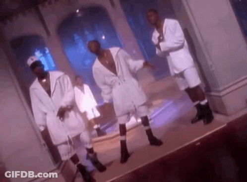 A Group Of Men In White Suits And Socks Are Dancing On A Stage In A Room . GIF