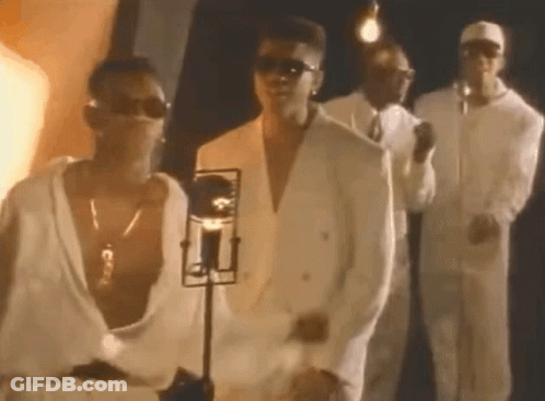 A Group Of Men In White Suits And Sunglasses Are Standing Next To Each Other In Front Of A Microphone . GIF