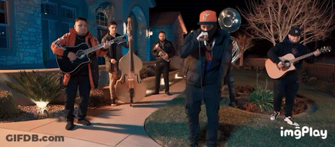 A Group Of Men Playing Instruments In Front Of A House With A Watermark That Says Imgplay GIF