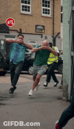 A Group Of Men Running Down A Street With A Red Sign That Says Aftv GIF