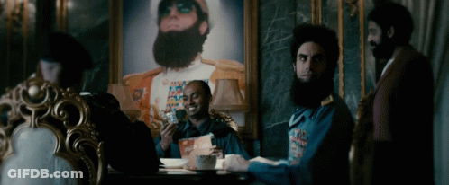 Men Sitting Around Table In Front Of Painting GIF
