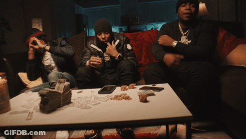 A Group Of Men Sit On A Couch With A Table Full Of Money GIF