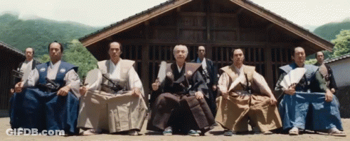 A Group Of Men Sitting In Front Of A Building GIF