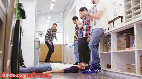 A Group Of Men Standing Around A Man Laying On The Floor With Esquire Written On The Bottom Right GIF