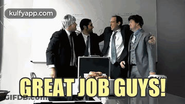 A Group Of Men Standing Around A Table With The Words Great Job Guys Written On It GIF