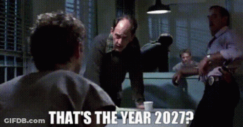 A Group Of Men Standing Around A Table With The Words " That 'S The Year 2027 " On The Bottom GIF