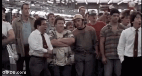 A Group Of Men Standing In A Line With Their Arms Crossed And One Man Wearing A Hard Hat GIF