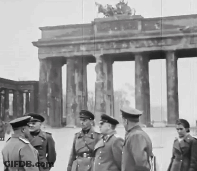 A Group Of Men Standing In Front Of A Building With Columns GIF