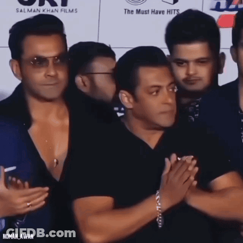 A Group Of Men Standing In Front Of A Sign That Says ' Salman Khan Films ' GIF