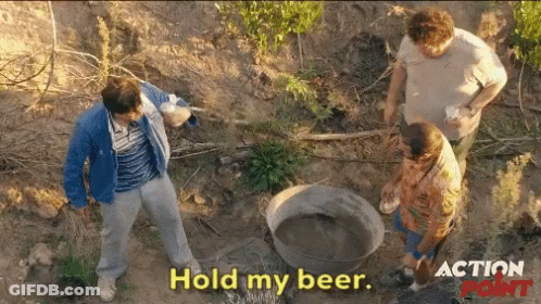 A Group Of Men Standing In The Dirt With The Words Hold My Beer On The Bottom GIF