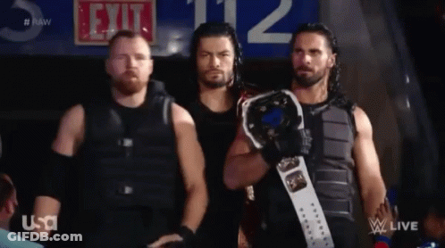 A Group Of Men Standing Next To Each Other Holding A Wrestling Championship Belt . GIF