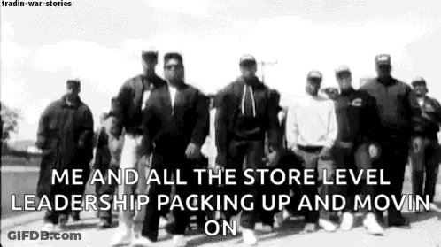 A Group Of Men Standing Next To Each Other On A Street . GIF