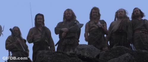 A Group Of Men Standing On Top Of A Rocky Hill With Their Arms In The Air . GIF