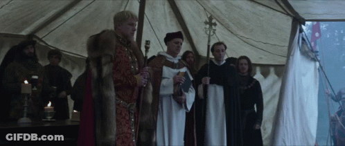 A Group Of Men Standing Under A Tent Holding Candles And A Cross GIF