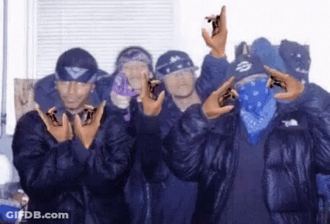 A Group Of Men Wearing Blue Jackets And Bandanas Are Standing Next To Each Other . GIF