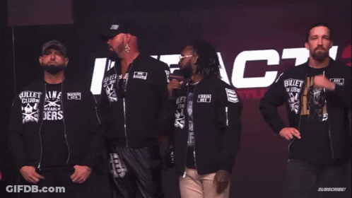 A Group Of Men Wearing Bullet Club Shirts Stand In Front Of A Sign That Says Do You Wanna Fight About It GIF
