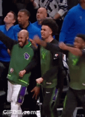 A Group Of Men Wearing Green And Black Jerseys Are Dancing In A Stadium GIF