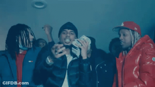 A Group Of Men Wearing Hooded Jackets Are Sitting In A Dark Room . GIF