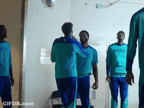 A Group Of Men Wearing Hornets Shirts Are Standing In A Hallway GIF