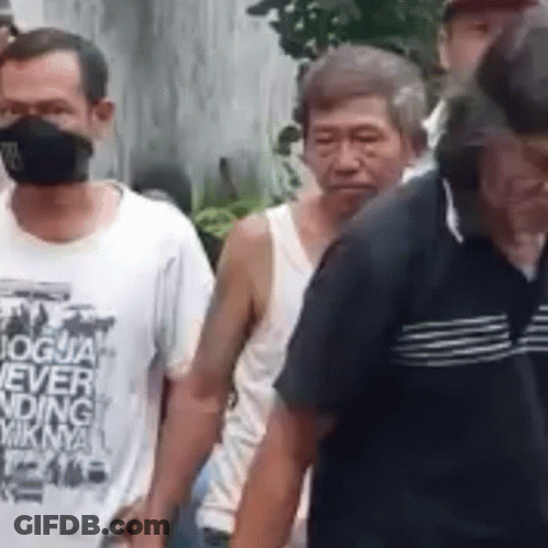 A Group Of Men Wearing Masks Are Walking In A Line . GIF